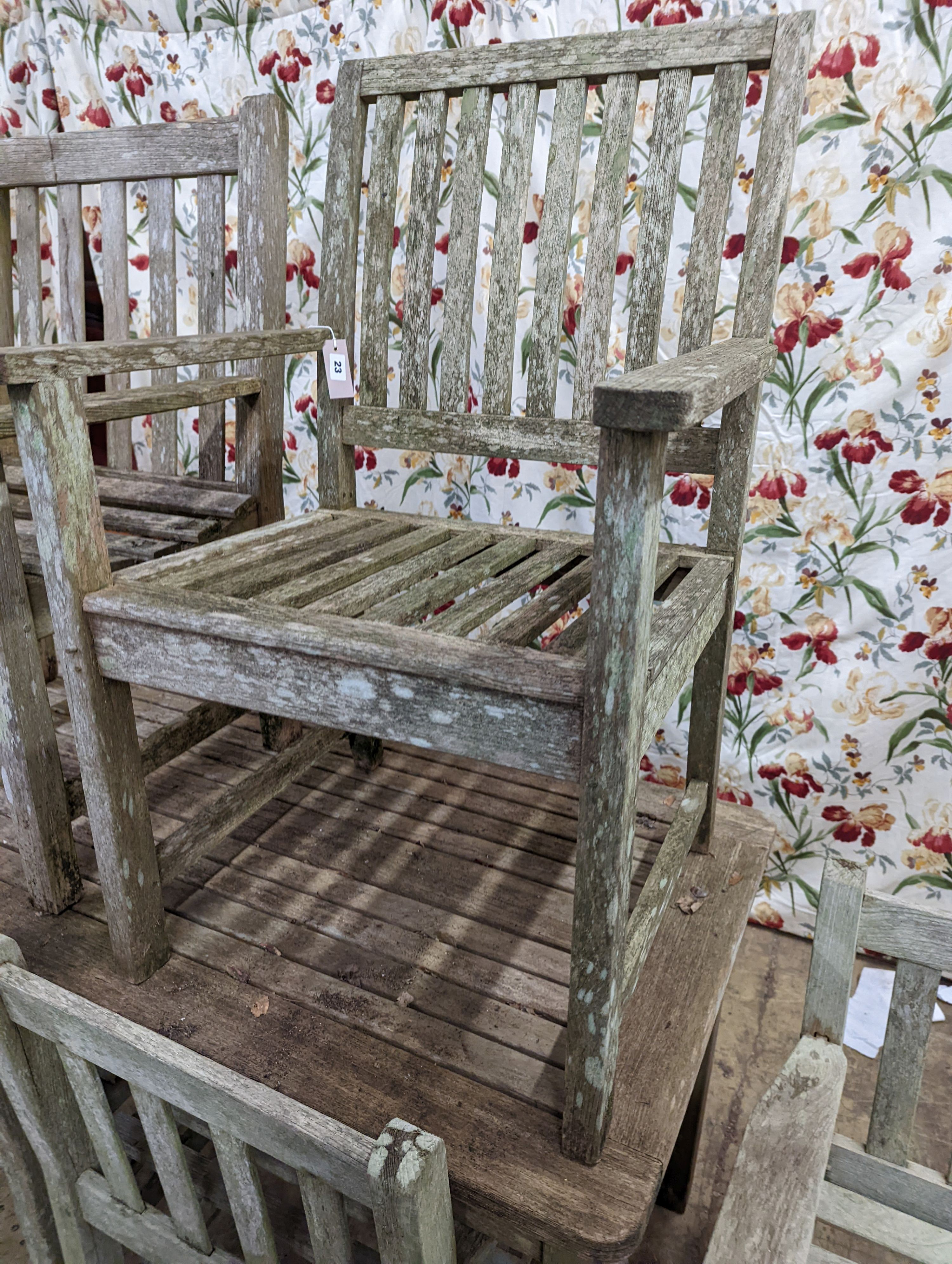 A weathered teak rectangular garden table and six elbow garden chairs, not matching. Table measures, W-149cm, D-70cm, H-75cm.
